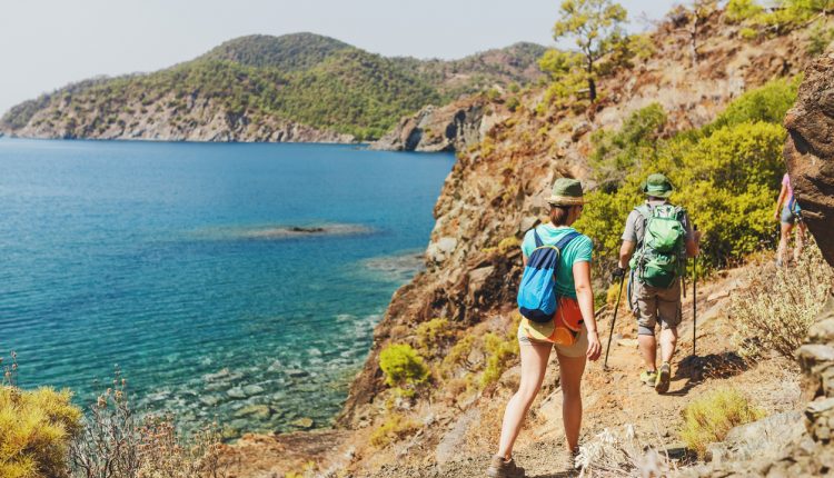 Group of Hikers walking by Lycian Way trail along wild beach and mountains in Turkey